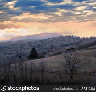 Winter coming. Last good weather days in autumn mountains countryside morning peaceful picturesque scene. Dirty road from hills to the village.