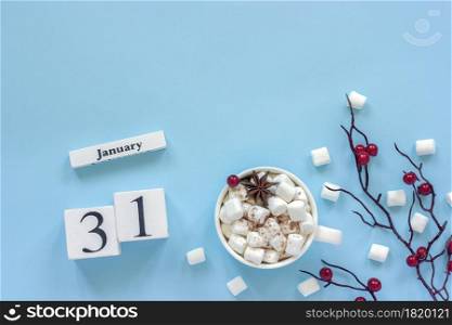 Winter composition. White wooden calendar cubes. Data January 31. Cup of cocoa, marshmallows and decorative branch with red berries on blue background Top view Flat lay Copy space. Calendar January 31 Cup of cocoa, marshmallows and branch berries
