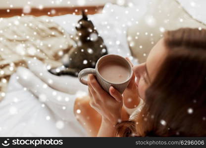 winter, cosiness, leisure and people concept - close up of happy young woman with cup of coffee or cacao and cat at home over snow. close up of happy woman with cup of cocoa at home