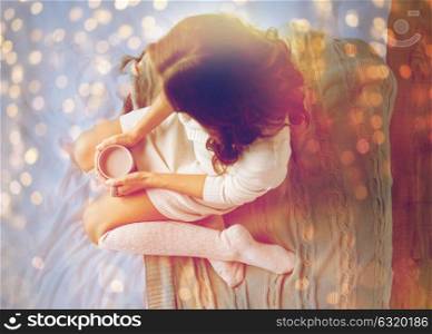 winter, coziness, leisure and people concept - young woman with cup of coffee or cacao in bed at home. woman with cocoa cup in bed at home