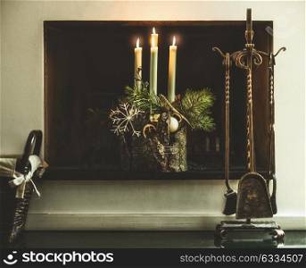 Winter cozy home decoration and festive atmosphere with burning candles, fir branches and snowflakes at fireplace in living room. Decorated Fourth Advent wreath