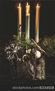 Winter cozy home decoration and festive atmosphere with burning candles, fir branches and snowflakes on dark background, front view. Decorated Fourth Advent wreath