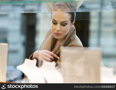 winter dressed woman , with coat , looking at window shop , she has reflection glass on face