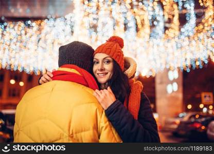 Winter evening, love couple hugs on the street. Man and woman having romantic meeting, happy relationship