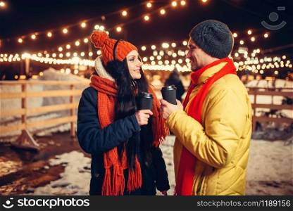 Winter evening, love couple walking outdoors, holiday illumination on background. Man and woman having romantic meeting on city street with lights. Winter evening, love couple walking outdoors