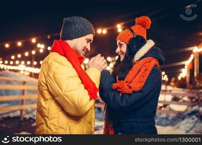Winter evening, love couple warm hands outdoors. Man and woman having romantic meeting on city street with lights. Winter evening, love couple warm hands outdoors