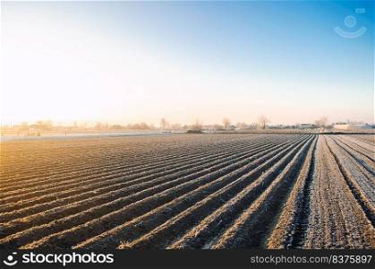 Winter farm field ready for new planting season. Agriculture and agribusiness. Preparatory agricultural work for spring. Choosing right time for sow fields plant seeds, protection from spring frosts.