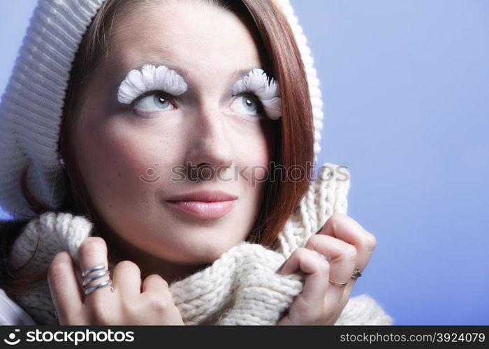 winter fashion beautiful woman in warm clothing stylish creative make up false long white eye lashes blue background