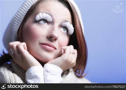 winter fashion beautiful woman in warm clothing stylish creative make up false long white eye lashes blue background