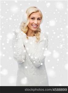 winter, fashion, christmas and people concept - smiling young woman in earmuffs and sweater