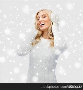 winter, fashion, christmas and people concept - smiling young woman in earmuffs and sweater
