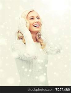 winter, fashion, christmas and people concept - smiling young woman in earmuffs and sweater. smiling young woman in winter earmuffs and sweater