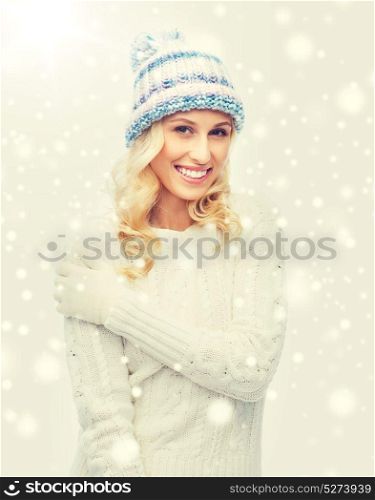 winter, fashion, christmas and people concept - smiling young woman in winter hat, sweater and gloves. smiling young woman in winter hat and sweater