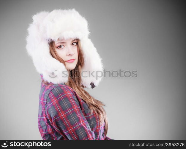 Winter fashion. Close up young woman wearing fashionable wintertime clothes white fur cap studio shot on gray background