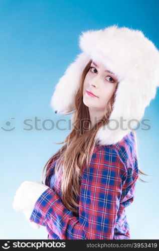 Winter fashion. Close up young woman wearing fashionable wintertime clothes white fur cap studio shot on blue background