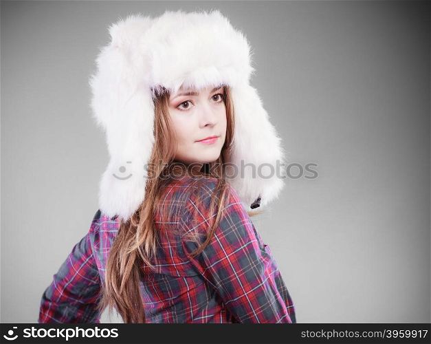 Winter fashion. Close up young woman wearing fashionable wintertime clothes white fur cap studio shot on gray background