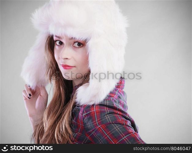 Winter fashion. Close up young woman wearing fashionable wintertime clothes white fur cap studio shot on gray background