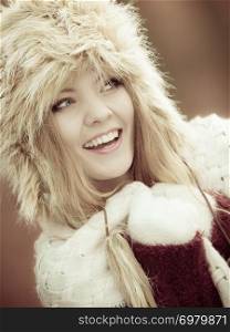 Winter fashion. Closeup smiling young woman wearing fashionable wintertime clothes fur cap outdoor portrait