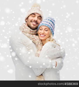 winter, fashion, couple, christmas and people concept - smiling man and woman in hats and scarf hugging