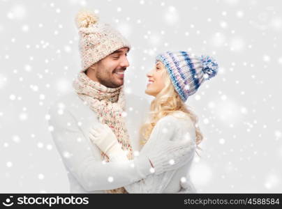 winter, fashion, couple, christmas and people concept - smiling man and woman in hats and scarf hugging