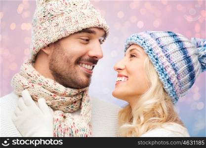 winter, fashion, couple, christmas and people concept - smiling man and woman in hats and scarf hugging over rose quartz and serenity lights background