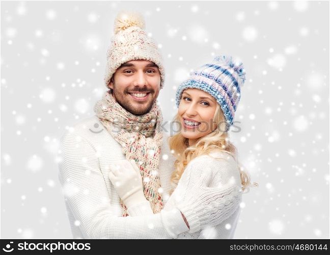 winter, fashion, couple, christmas and people concept - smiling man and woman in hats and scarf hugging