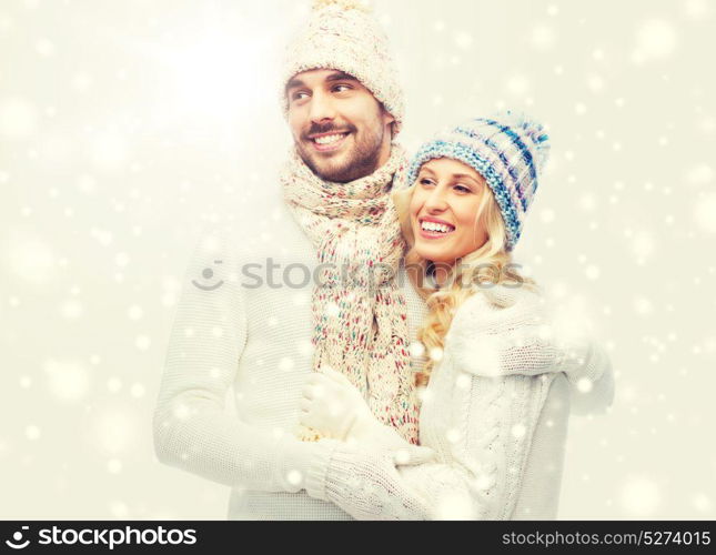 winter, fashion, couple, christmas and people concept - smiling man and woman in hats and scarf hugging. smiling couple in winter clothes hugging