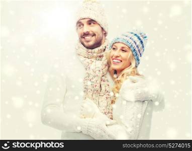 winter, fashion, couple, christmas and people concept - smiling man and woman in hats and scarf hugging. smiling couple in winter clothes hugging