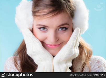 Winter fashion ear protection. Portrait positive teen girl in warm clothes. Happy woman in white earmuffs and mittens on blue