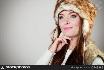 Winter fashion. Happy young woman wearing fashionable wintertime clothes fur cap studio shot on gray background