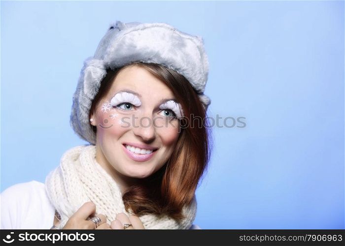 winter fashion woman in warm clothing fur hat stylish creative make up false long white eye lashes blue background