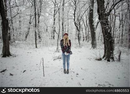 Winter fashion woman posing in the snowy forest wearing a warm fur jacket