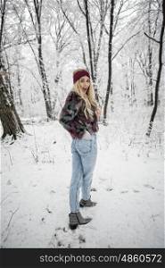 Winter fashion woman posing in the snowy forest wearing a warm fur jacket