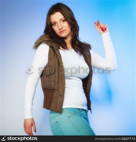 Winter fashion. Young woman plus size model posing in warm waistcoat studio shot on blue