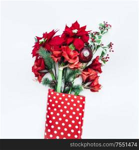 Winter flowers bunch of Amaryllis, Poinsettia and fir branches in red polka dot wrapping paper on white desktop . Top view. Christmas flowers arrangement
