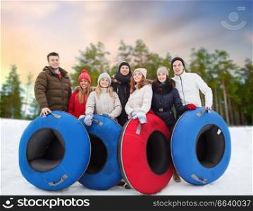 winter, friendship and entertainment concept - group of happy friends with snow tubes over natural background. happy friends with snow tubes outdoors in winter