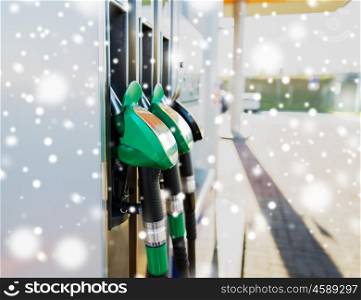 winter, fuel, oil, tank and transport concept - close up of gasoline hose at gas station over snow