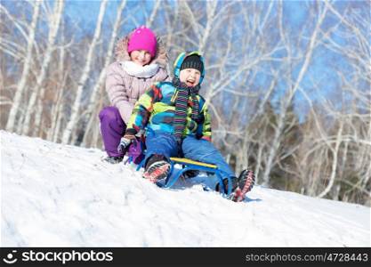 Winter fun. Boy and girl enjoying sledge ride in beautiful snowy winter park