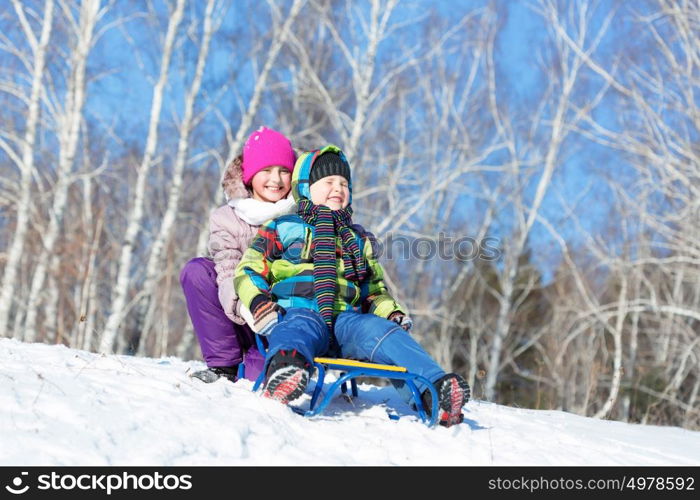 Winter fun. Boy and girl enjoying sledge ride in beautiful snowy winter park