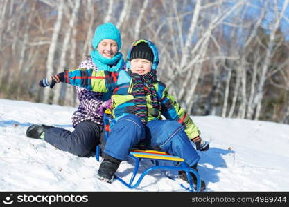 Winter fun. Boy and girl enjoying sledge ride in beautiful snowy winter park