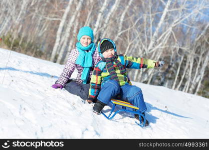 Winter fun. Boy and girl enjoying sledge ride in beautiful snowy winter park