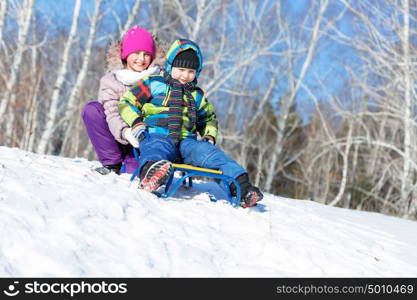 Winter fun. Boy and girl enjoying sledge ride in beautiful snowy winter park