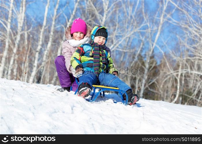 Winter fun. Boy and girl enjoying sledge ride in beautiful snowy winter park