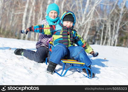 Winter fun. Boy and girl enjoying sledge ride in beautiful snowy winter park