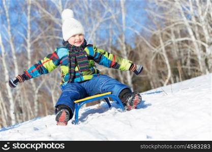 Winter fun. Boy enjoying sledge ride in beautiful snowy winter park