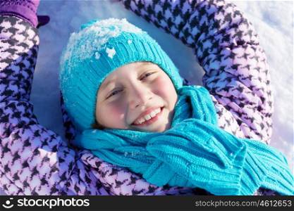 Winter fun. Happy kid lies on snow in winter park