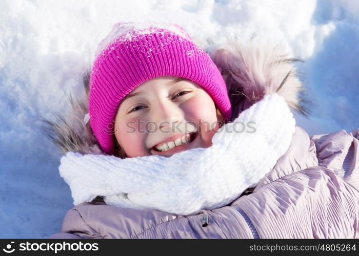 Winter fun. Happy kid lies on snow in winter park