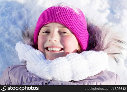 Winter fun. Happy kid lies on snow in winter park