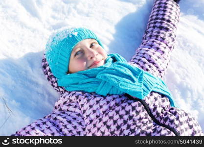 Winter fun. Happy kid lies on snow in winter park