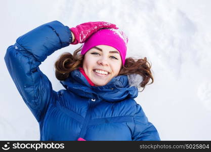 Winter fun. Happy young woman lying on snow in winter forest